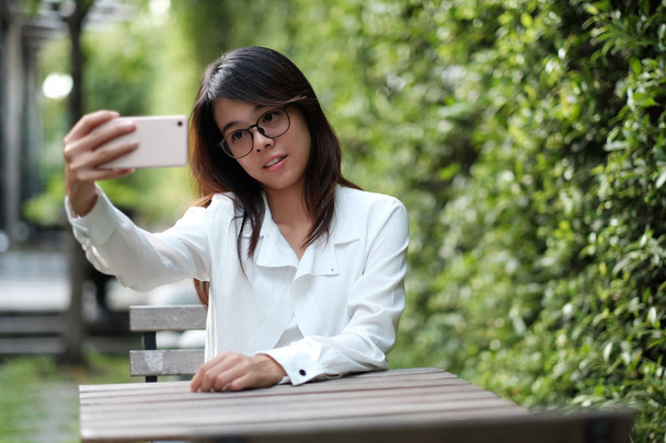 fiatal nő ül a zöld kert és h szemüveg - Fotó, kép