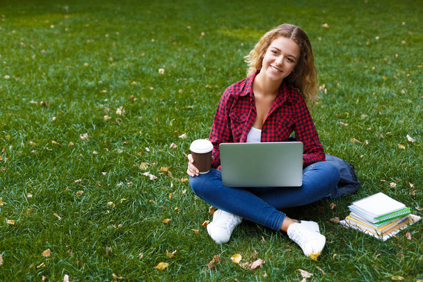 Mujer joven sonriente con portátil al aire libre
 - Foto, imagen