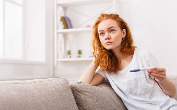 Strach, dívka s těhotenský test sedí na pohovce - Fotografie, Obrázek