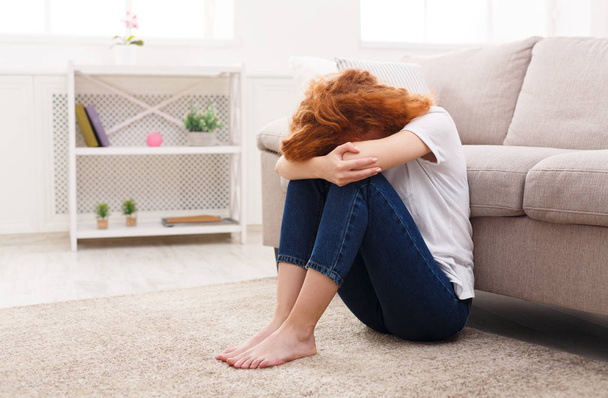 Λυπημένη γυναίκα που κάθεται μόνη στο πάτωμα - Φωτογραφία, εικόνα