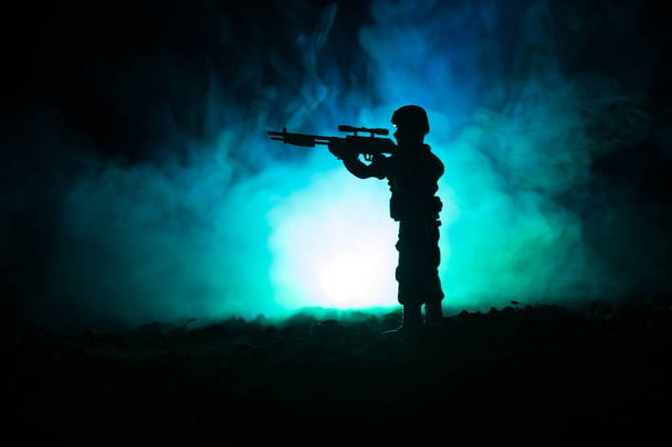 Sziluettjét katonai mesterlövész mesterlövész fegyver: sötét tónusú ködös háttér. lövés, holding a fegyvert, a színes ég, a háttérben - Fotó, kép