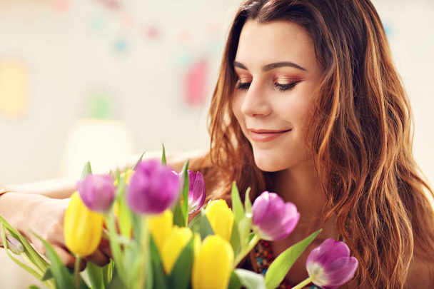 Mulher atraente organizando flores de tulipas em vaso
 - Foto, Imagem