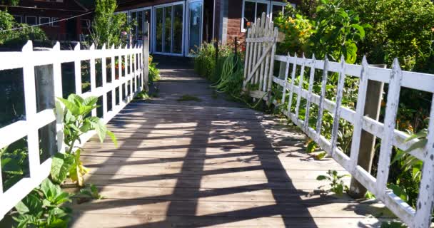 Anglická zahrada s bílým plotem, most, tropická vegetace a dřevěné Hostel se nachází v horské vesnici  - Záběry, video