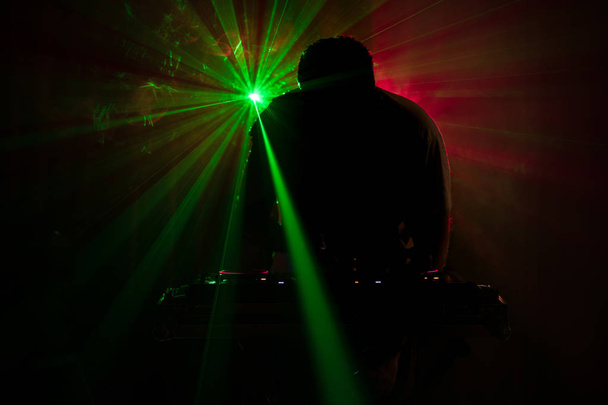 DJ κλώση, ανάμειξη και ξύσιμο σε ένα νυχτερινό κλαμπ, τα χέρια του dj τσίμπημα διάφορα στοιχεία ελέγχου γραμμής dj του καταστρώματος, strobe φώτα και ομίχλη ή μίξεις Dj στην πίστα σε νυχτερινό κέντρο διασκέδασης στο κόμμα - Φωτογραφία, εικόνα