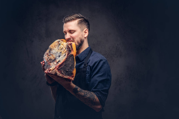 Professional butcher with raw smoked meat in a studio. - Фото, изображение