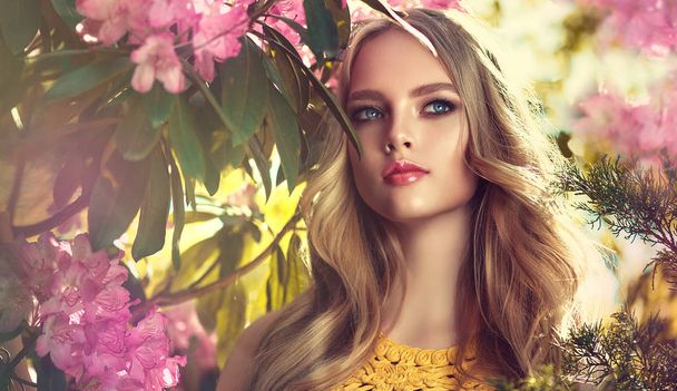 Güzel bahar modeli kız yaz çiçeği parkta güzel kokulu çiçekler. Kadın bir çiçek bahçesinde. Moda, kozmetik ve parfümler. Kıvırcık sarı saçlı - Fotoğraf, Görsel