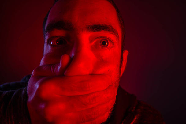 Close-up van een hand die betrekking hebben op de mond van een man met doodsbang facia mans - Foto, afbeelding