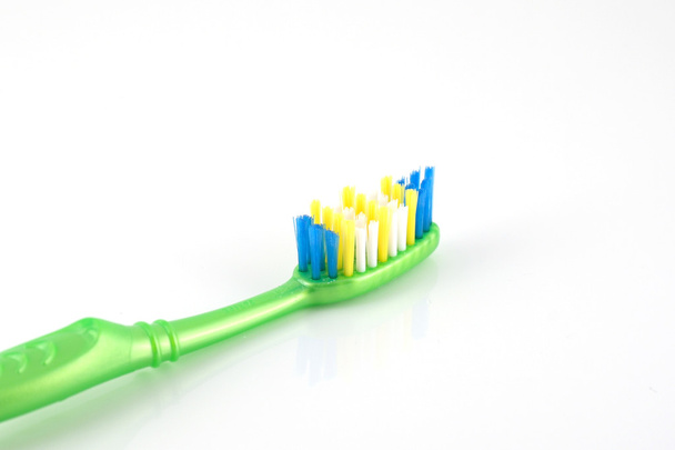 Cepillo de dientes con mango verde sobre blanco
 - Foto, Imagen