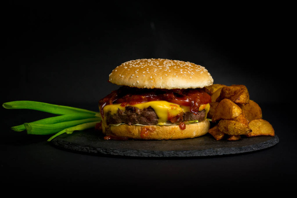 Close-up of fresh tasty burger and french fries  on a dark backg - Foto, Imagem