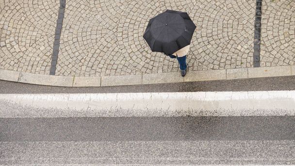 Personne tenant un parapluie dans la rue
. - Photo, image