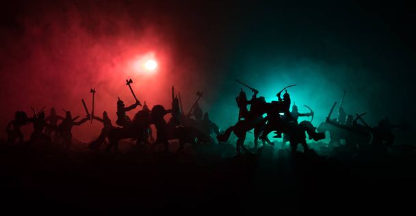 Μεσαιωνική μάχη σκηνή με ιππικό και πεζικό. Σιλουέτες των αριθμών ως ξεχωριστά αντικείμενα, καταπολέμηση μεταξύ πολεμιστές σε σκούρο τονισμένο ομιχλώδες φόντο. Σκηνή νύχτα. - Φωτογραφία, εικόνα