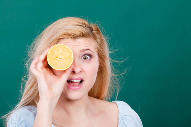 Girl covering her eye with lemon citrus fruit - Fotoğraf, Görsel
