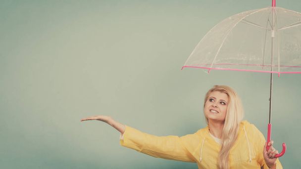 Woman wearing raincoat holding umbrella checking weather - Foto, Bild