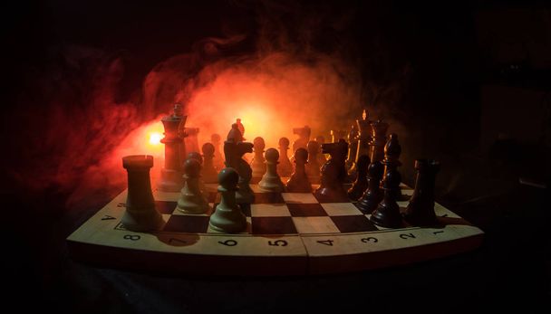 Концепция шахматных настольных игр бизнес-идей, конкуренции и стратегических идей. Шахматные фигуры на темном фоне с дымом и туманом. Концепция лидерства и доверия
. - Фото, изображение