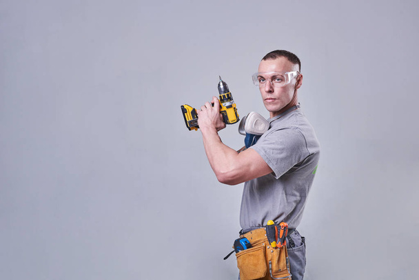 Master Builder-finalizador en ropa de trabajo, con un destornillador de taladro en la mano
 - Foto, imagen