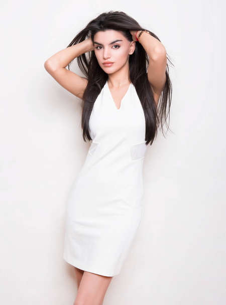beautiful young woman with long black hair wearing dress and posing on white background - Foto, Imagem