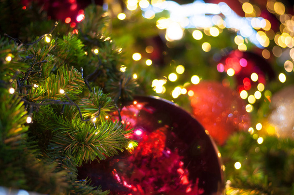 Fechar grande bola de glitter vermelho natal na árvore com fio fundo de luz branca
 - Foto, Imagem