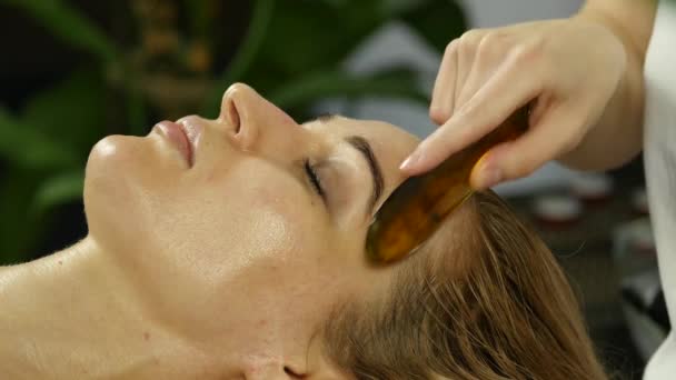 beautician does facial massage for beautiful woman in spa saloon. 4K - Felvétel, videó