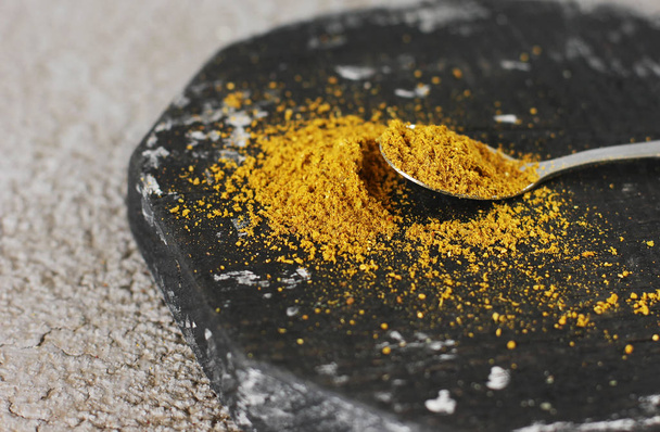 Kurkuma-Curry-Pulver in einem Löffel auf Holzgrund - Foto, Bild
