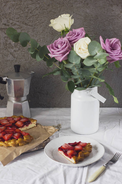 Eettafel met bloemen, koffie-/ theevoorzieningen en aardbei taart - Foto, afbeelding