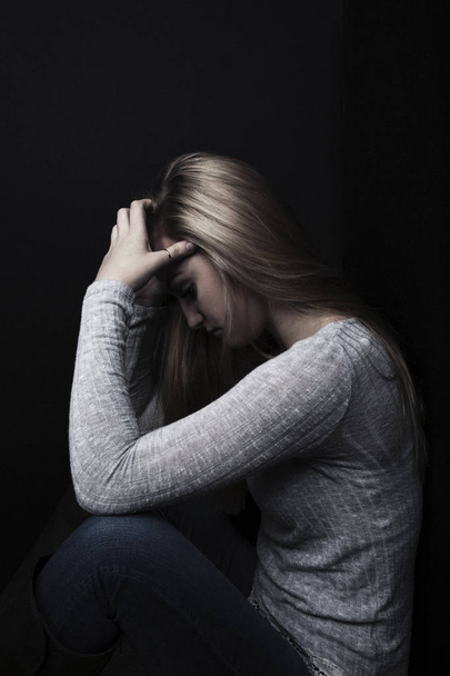 Profil dospívající dívka sedí s hlavou v dlaních ve stínu. - Fotografie, Obrázek