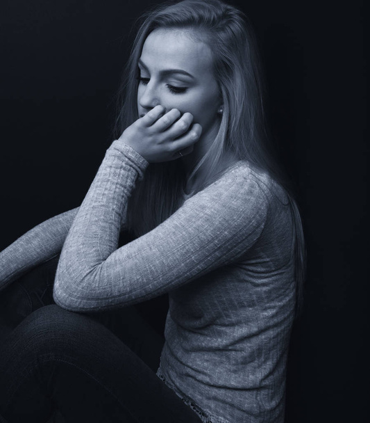 Jolie adolescente blonde regardant triste avec une main sur son visage
. - Photo, image