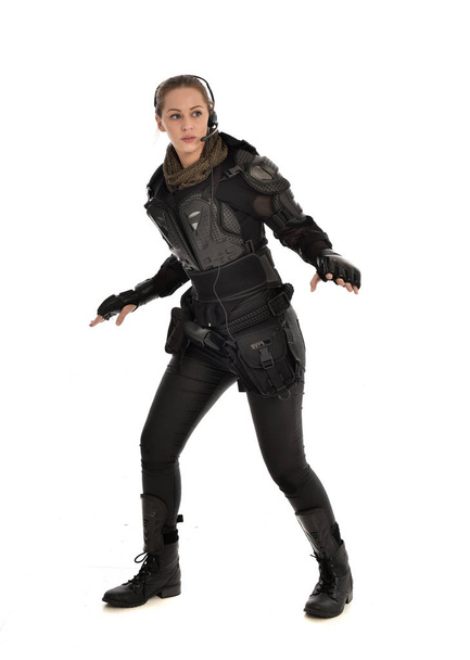 Ganzes Porträt einer Soldatin in schwarzer taktischer Rüstung, isoliert auf weißem Studiohintergrund. - Foto, Bild