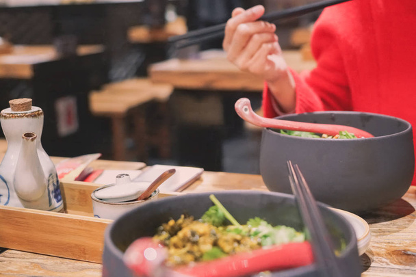 Blur beweging van het rode shirt vrouwenhand Hold eetstokjes eten noodle - Foto, afbeelding