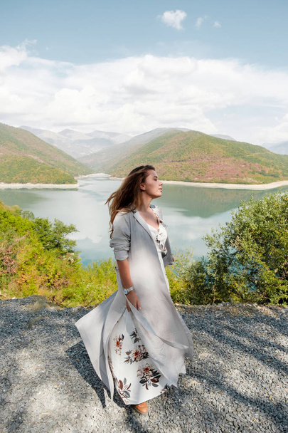 Beautiful girl in a long dress on a background of a lake and mountains - Valokuva, kuva