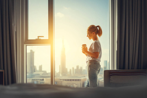 счастливая молодая женщина пьет кофе утром у окна
 - Фото, изображение