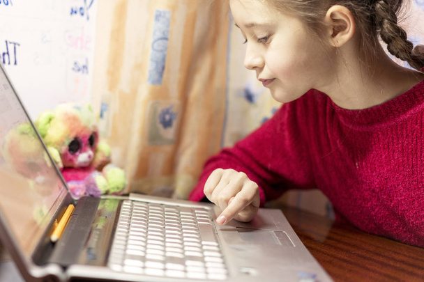 8-летняя девочка делает домашнее задание на ноутбуке
 - Фото, изображение