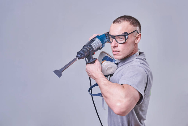 Maître Constructeur-finisseur en vêtements de travail, avec une perforatrice dans les mains - Photo, image