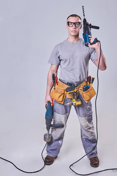 Master-Builder-finalizador en su ropa de trabajo, con dos martillos en sus manos
 - Foto, imagen