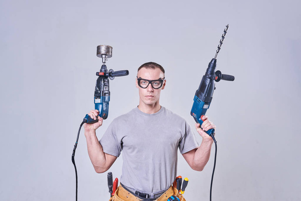 Мастер-строитель-финишер в рабочей одежде, с двумя молотками в руках
 - Фото, изображение