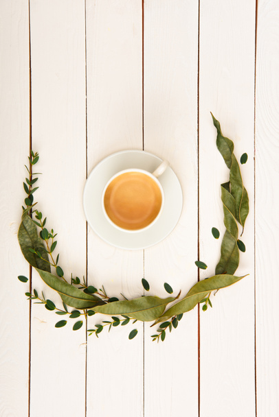 top view of floral wreath and cup of coffee on wooden tabletop - Фото, зображення