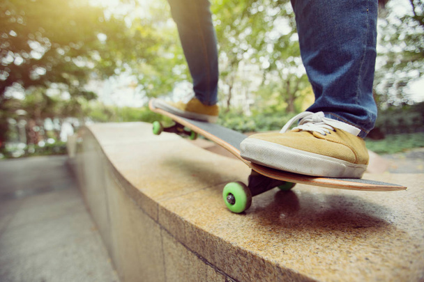 young skateboarder legs riding skateboard at city skatepark - Фото, изображение