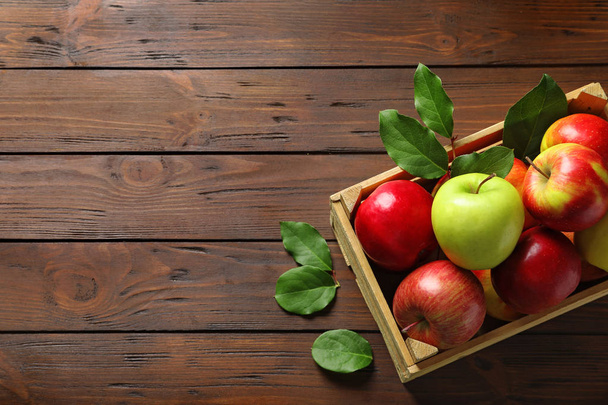 Wooden crate with ripe juicy apples on table - Fotó, kép