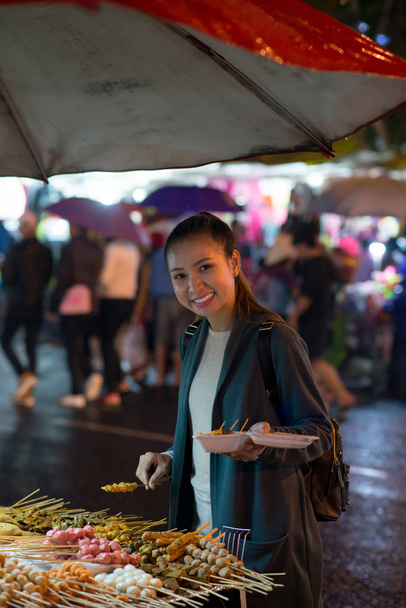 Glimlachend grijpen voedsel van de jonge vrouw op lokale markt - Foto, afbeelding