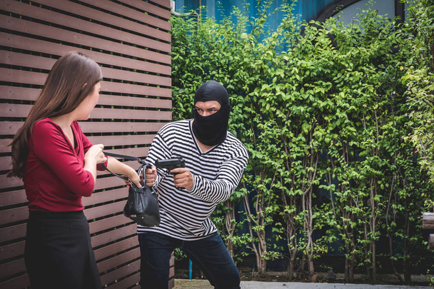 Tolvaj fenyegető fegyvert, fiatal nő küzdelem több mint a rabló, aki lopás táska. - Fotó, kép