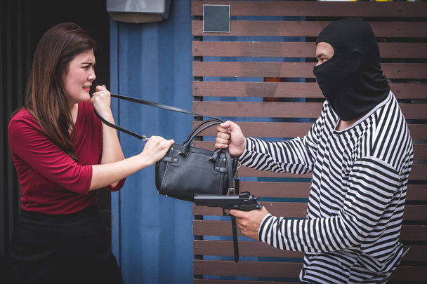 Dief bedreigt met pistool, jonge vrouw strijd met Rover die stelen tas. - Foto, afbeelding