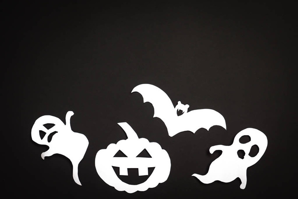 Halloween vakantie achtergrond met pompoen, spoken en vleermuis snijdt papier op zwarte achtergrond. Vrije ruimte voor tekst. - Foto, afbeelding