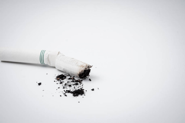Rabo de cigarro com cinzas em um fundo branco. Espaço livre para texto
 - Foto, Imagem