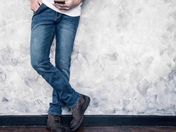 Primer plano de las piernas del hombre en jeans y botas en piso de madera. Espacio libre para texto
 - Foto, Imagen