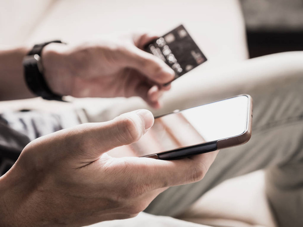 Lähikuva miesten käsissä älypuhelimella ja pitämällä luottokorttia. Verkkokaupoissa käsite. valikoiva kohdentaminen
 - Valokuva, kuva