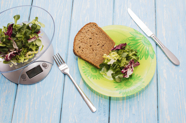 Salada deliciosa de ervas verdes em uma chapa, escalas de cozinha. O conceito de nutrição adequada. Dieta
 - Foto, Imagem