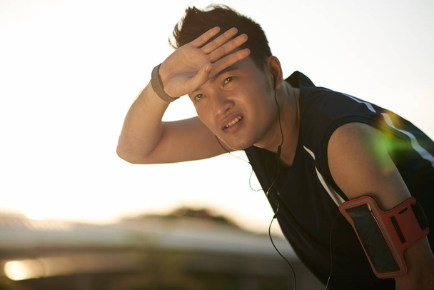 Młody człowiek Asian zmęczony po joggingu na zewnątrz - Zdjęcie, obraz