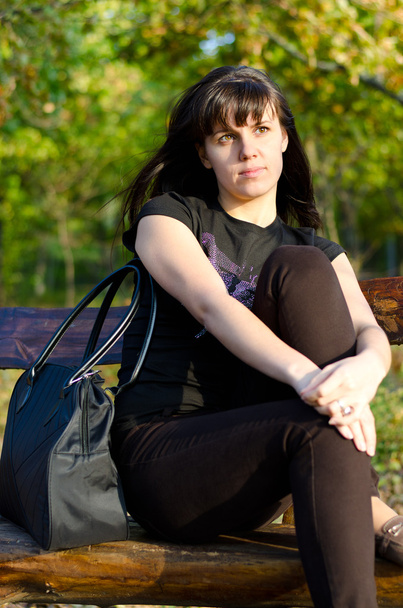 Mujer joven y casual sentada en un banco
 - Foto, Imagen