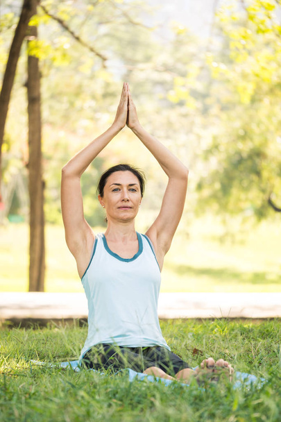 Krásná žena, která dělá cvičení jógy v parku. Koncept zdravého životního stylu. - Fotografie, Obrázek