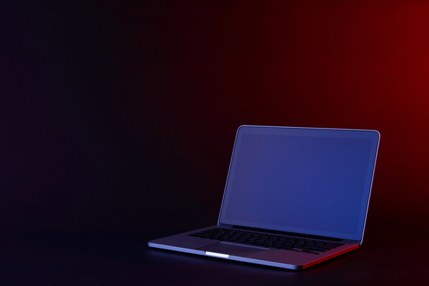 один открытый ноутбук с отражающим экраном на темной поверхности
 - Фото, изображение