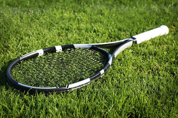 Modern tennis racket on green grass - Photo, image